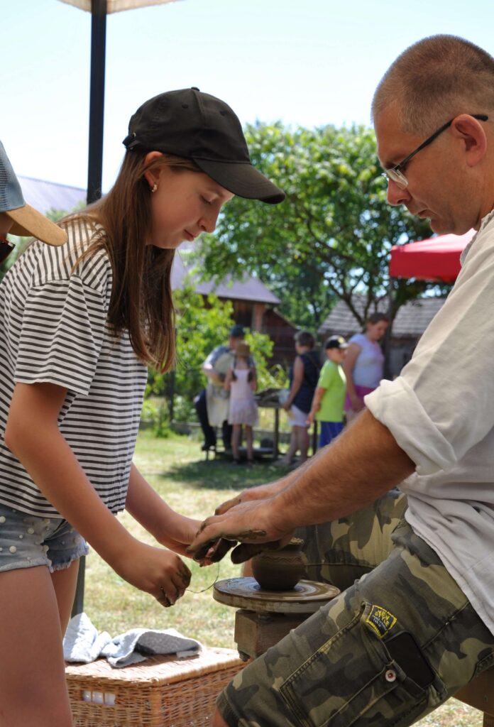 Mężczyzna i dziewczynka pracują nad ceramiką na kole garncarskim.