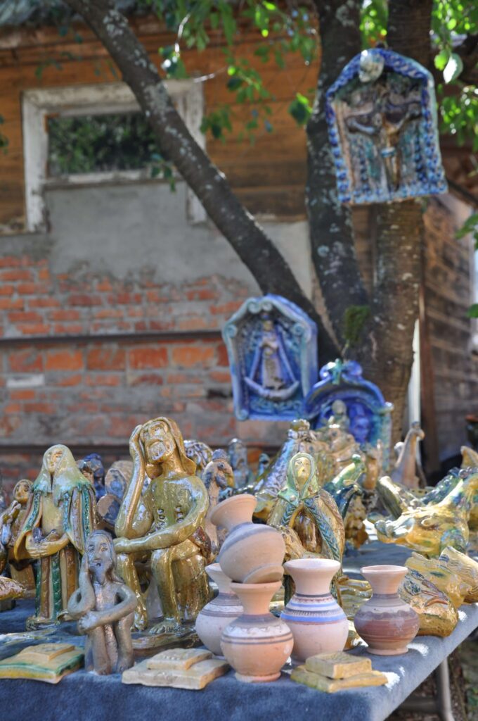 Stół z wieloma rzeźbami i wazonami, różnorodne kształty i kolory, tworzące estetyczną kompozycję.