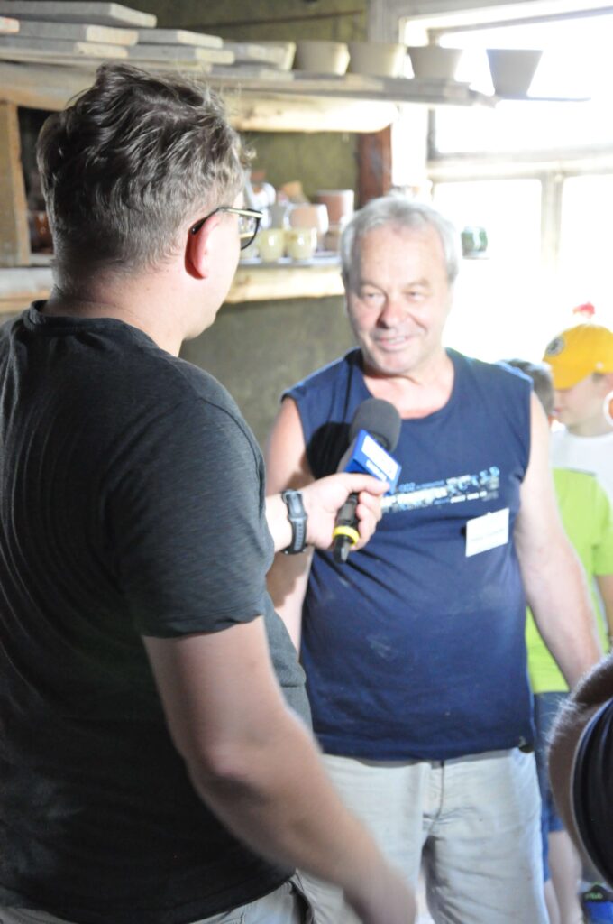 Dwóch mężczyzn rozmawia, jeden trzyma mikrofon.