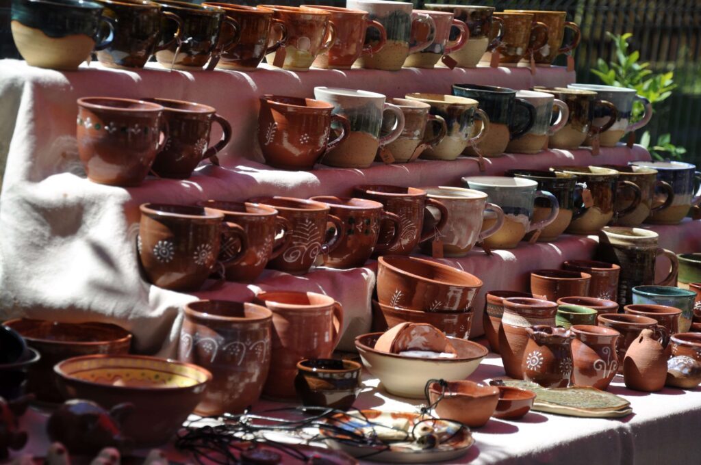 Stół z wieloma filiżankami w różnych kolorach i wzorach, ustawionymi w porządku na półkach.