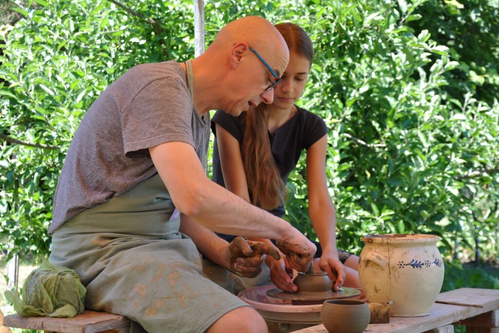 Mężczyzna i dziewczynka pracują nad ceramiką na kole garncarskim.