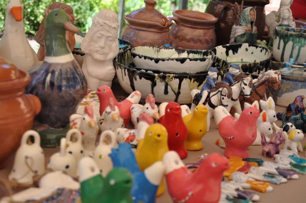 Stół z wieloma ceramicznymi figurkami, różnorodne kształty i kolory.