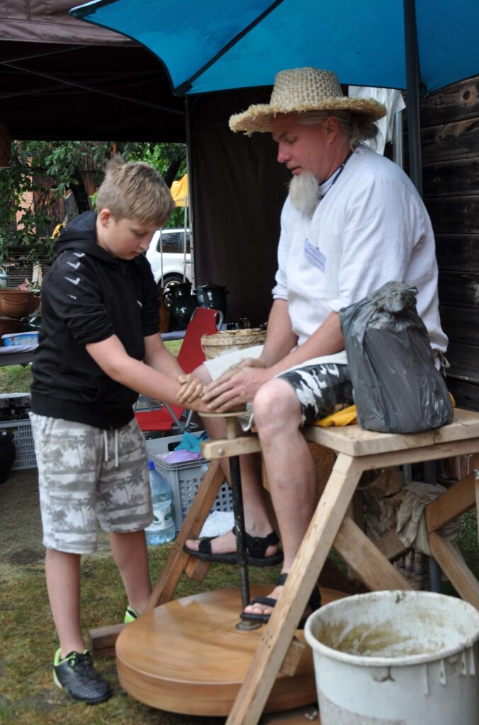 Mężczyzna i chłopiec pracują nad ceramiką na kole garncarskim.
