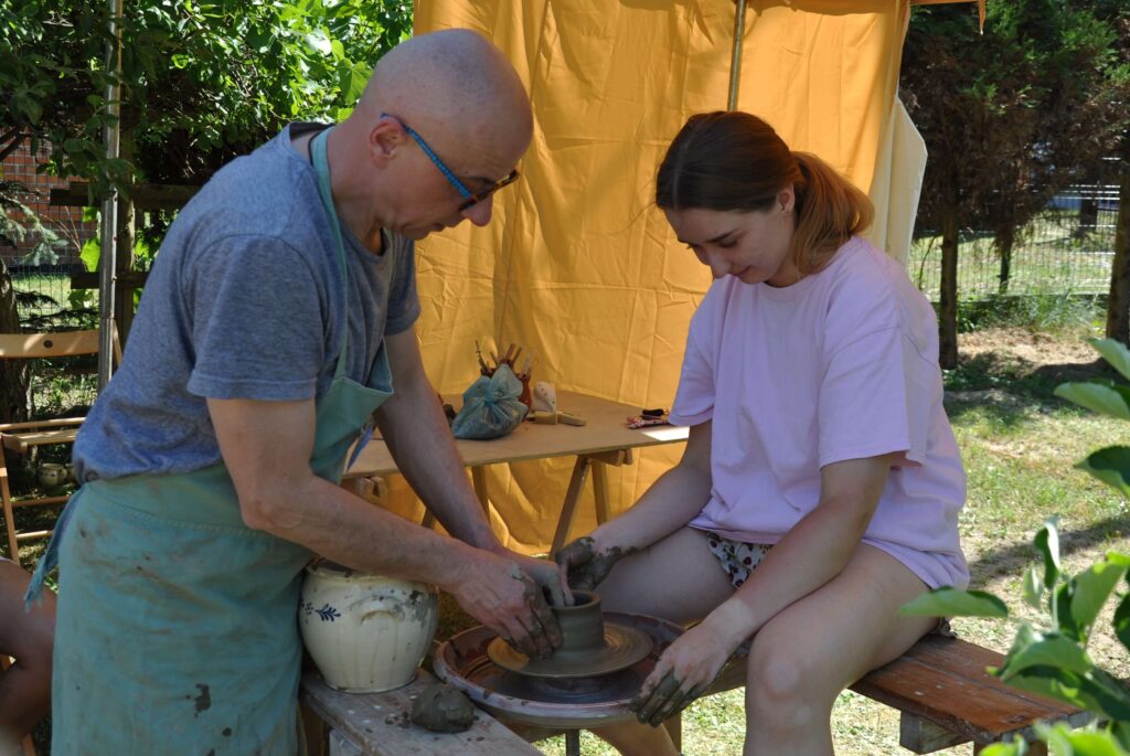 Mężczyzna i młoda kobieta pracują nad ceramiką na kole garncarskim.