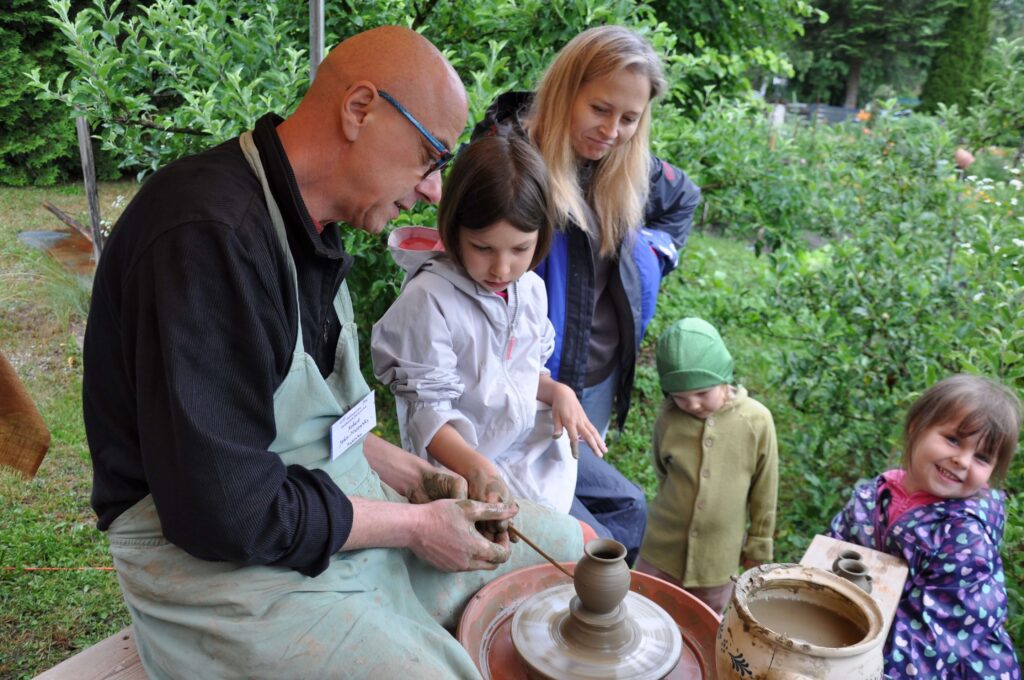 Mężczyzna i kobieta tworzą ceramikę z dziećmi, wspólnie bawiąc się w twórczym procesie.