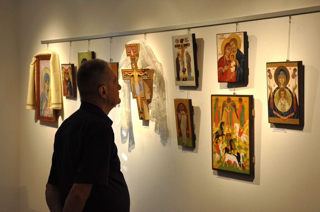 Mężczyzna ogląda z zainteresowaniem kolorowe ikony zawieszone na ścianie.