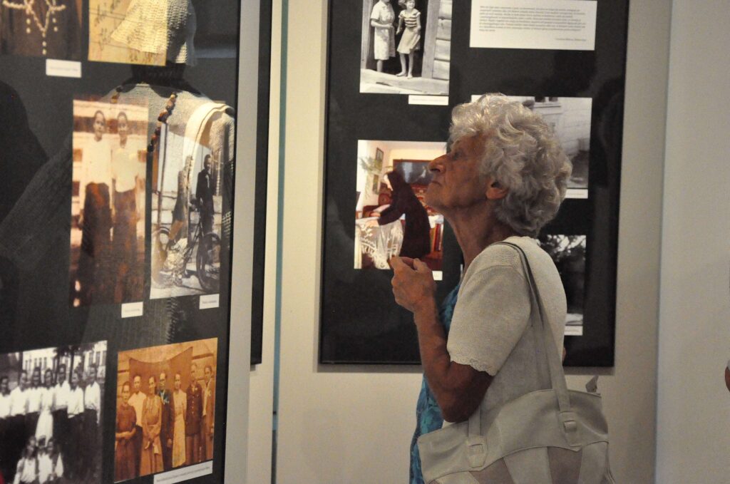 Starsza kobieta ogląda fotografie prezentowane na ścianie