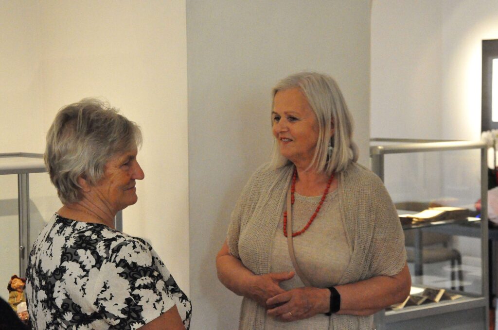 Dwie kobiety rozmawiają na tle białej ściany