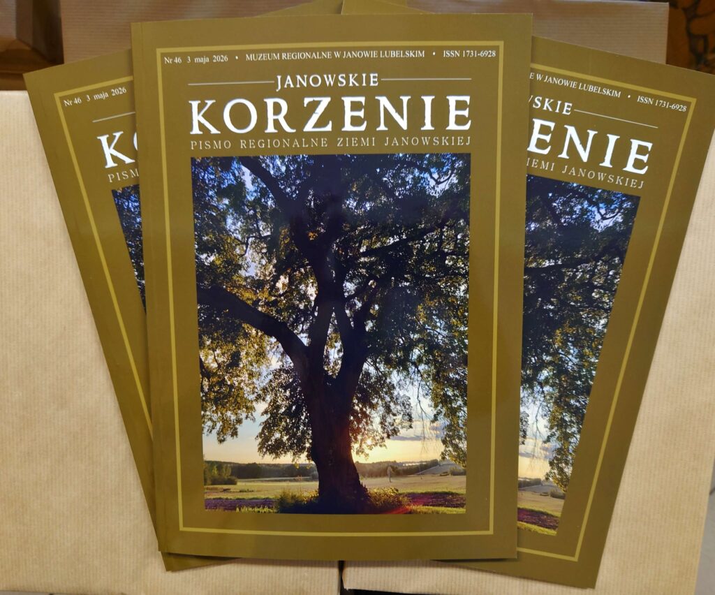 Okładki czasopisma o oliwkowym tle z dużym białym napisem "KORZENIE" oraz zdjęciem dużego drzewa na tle zachodzącego słońca i pola.